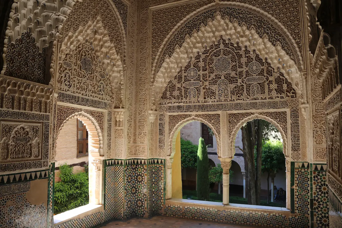 The Alhambra in Granada, Spain, showcasing its iconic red walls, intricate Islamic architectural details, and the lush Generalife gardens in the backdrop.