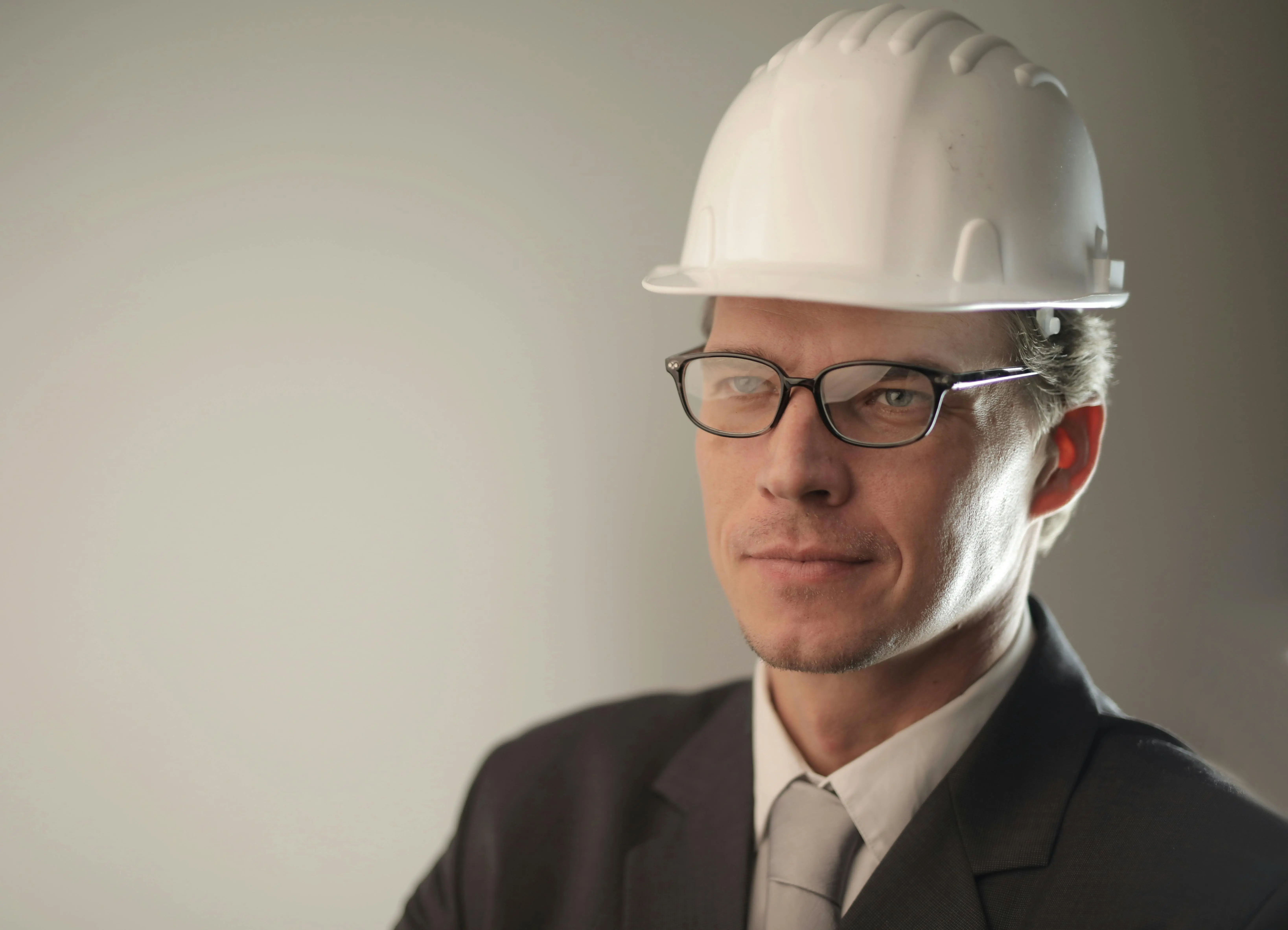 A confident architect wearing a helmet poses for a portrait in a professional setting.