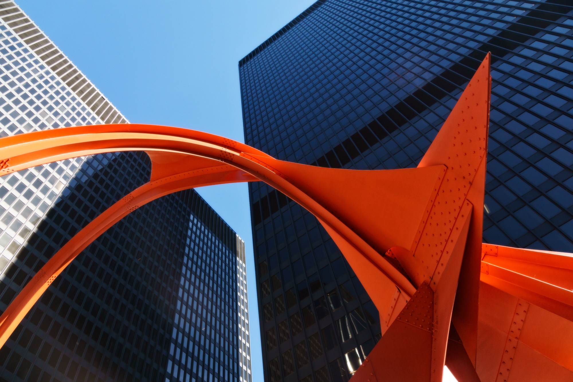 contrast of sleek steel structures and the vibrant red Flamingo sculpture at the Federal Center designed by Ludwig Mies van der Rohe