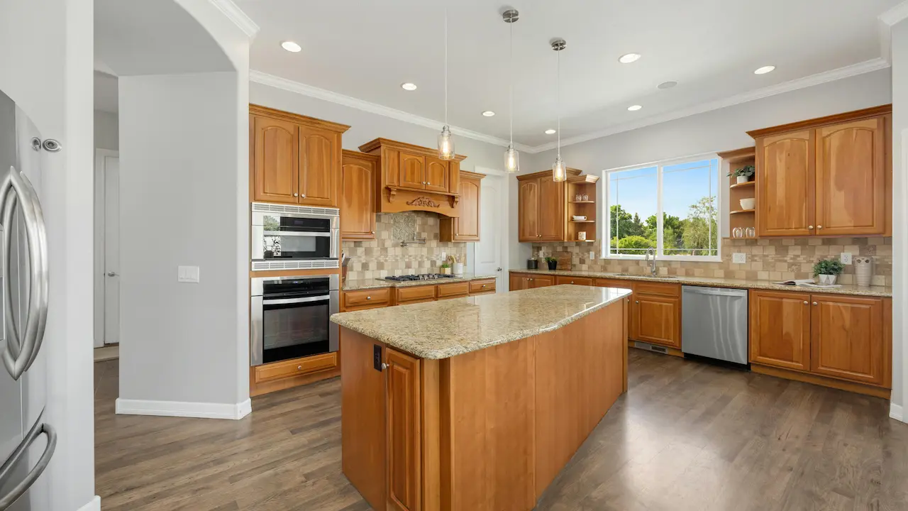 spacious kitchen with wooden furniture, windows, natural light, and many artificial lights