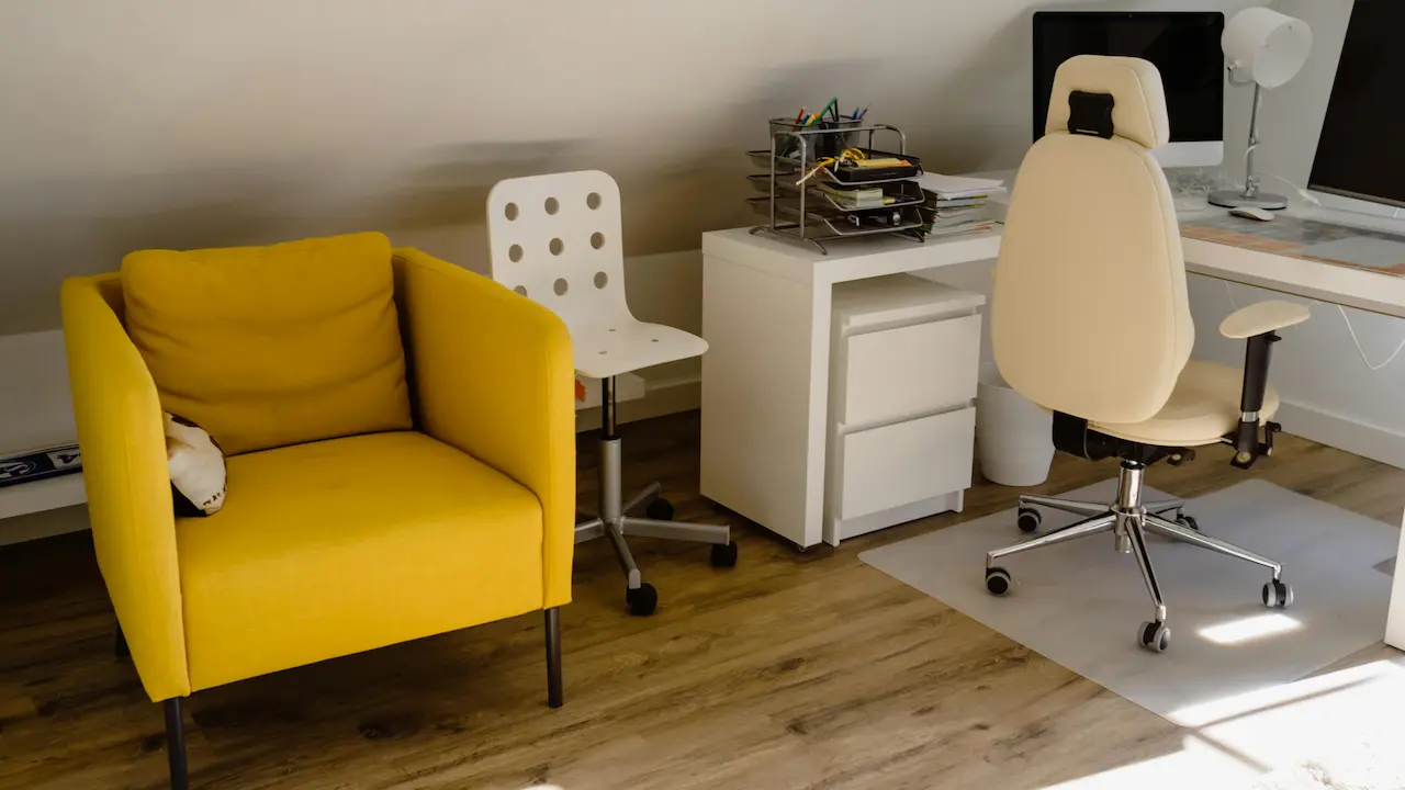 White and black rolling chair beside a white wooden desk in a modern workspace.