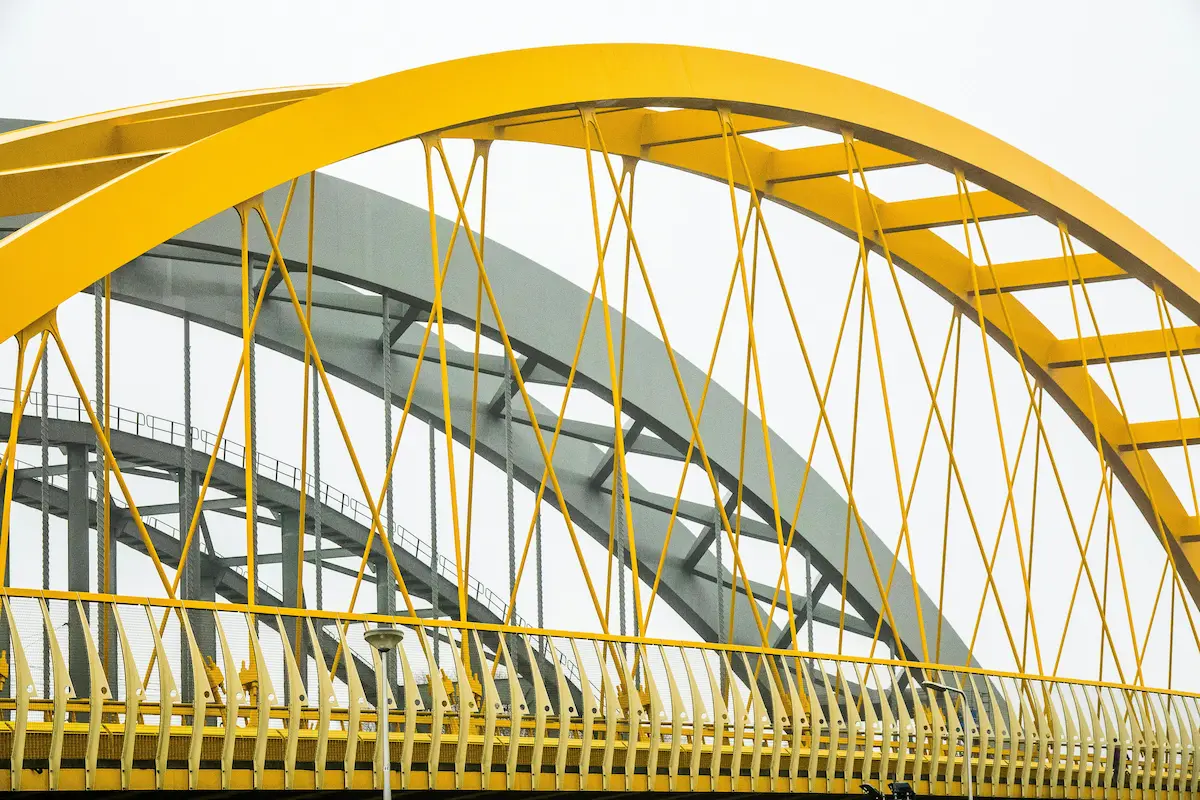 A metal arches of a bridge with yellow colors creating a visually striking accent.