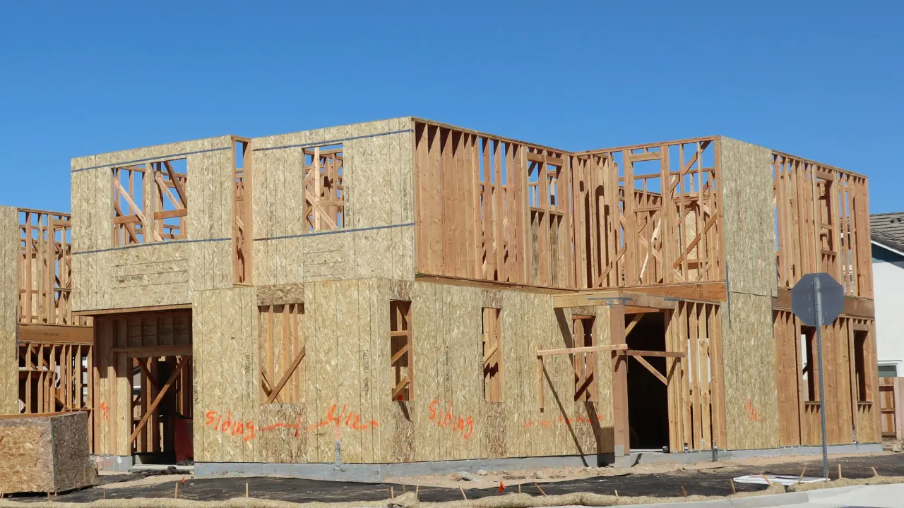A large house under construction, showing its wooden framing structure in the early building stage.