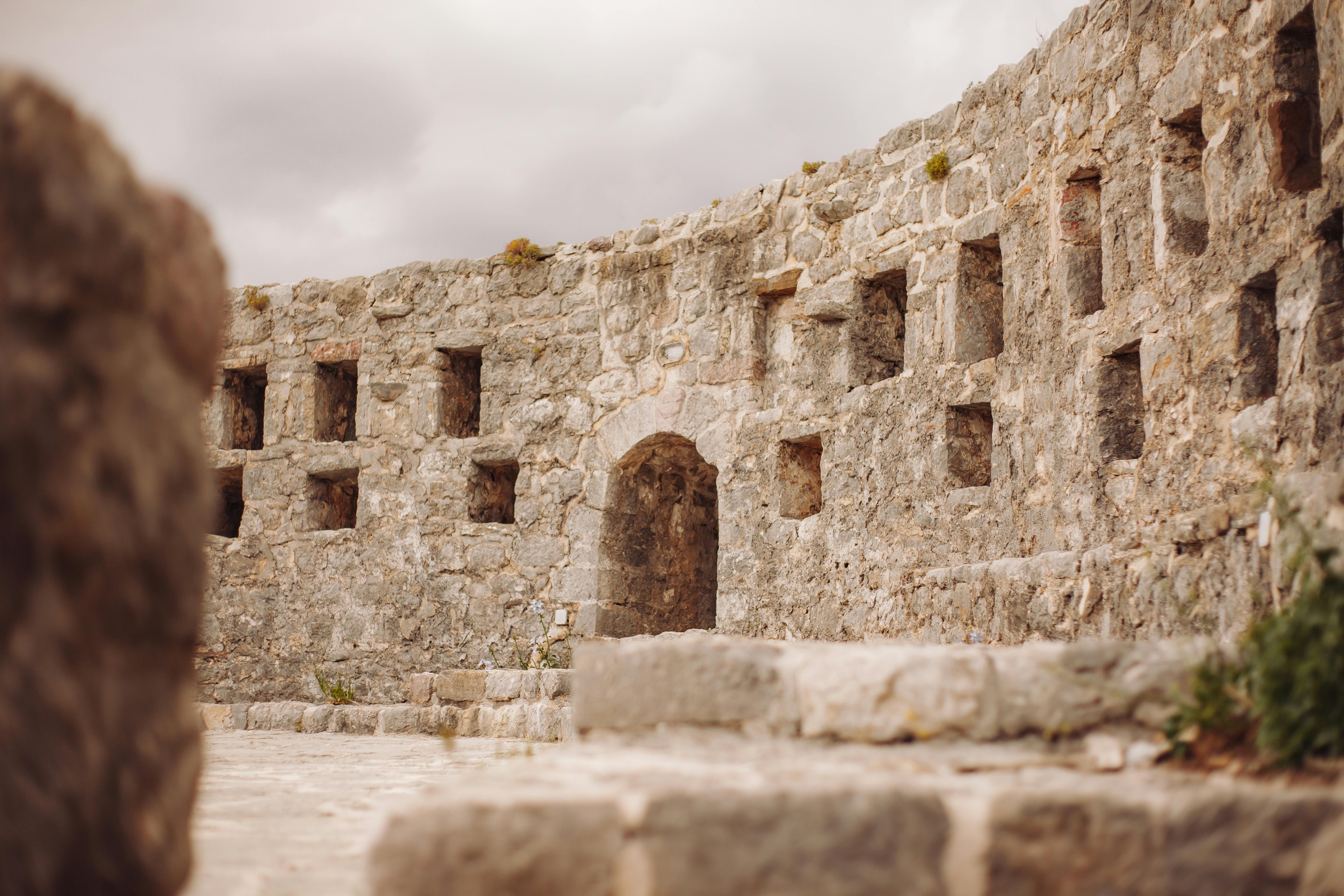 Abandoned Romanesque stone building, featuring arches, pillars, and weathered details.