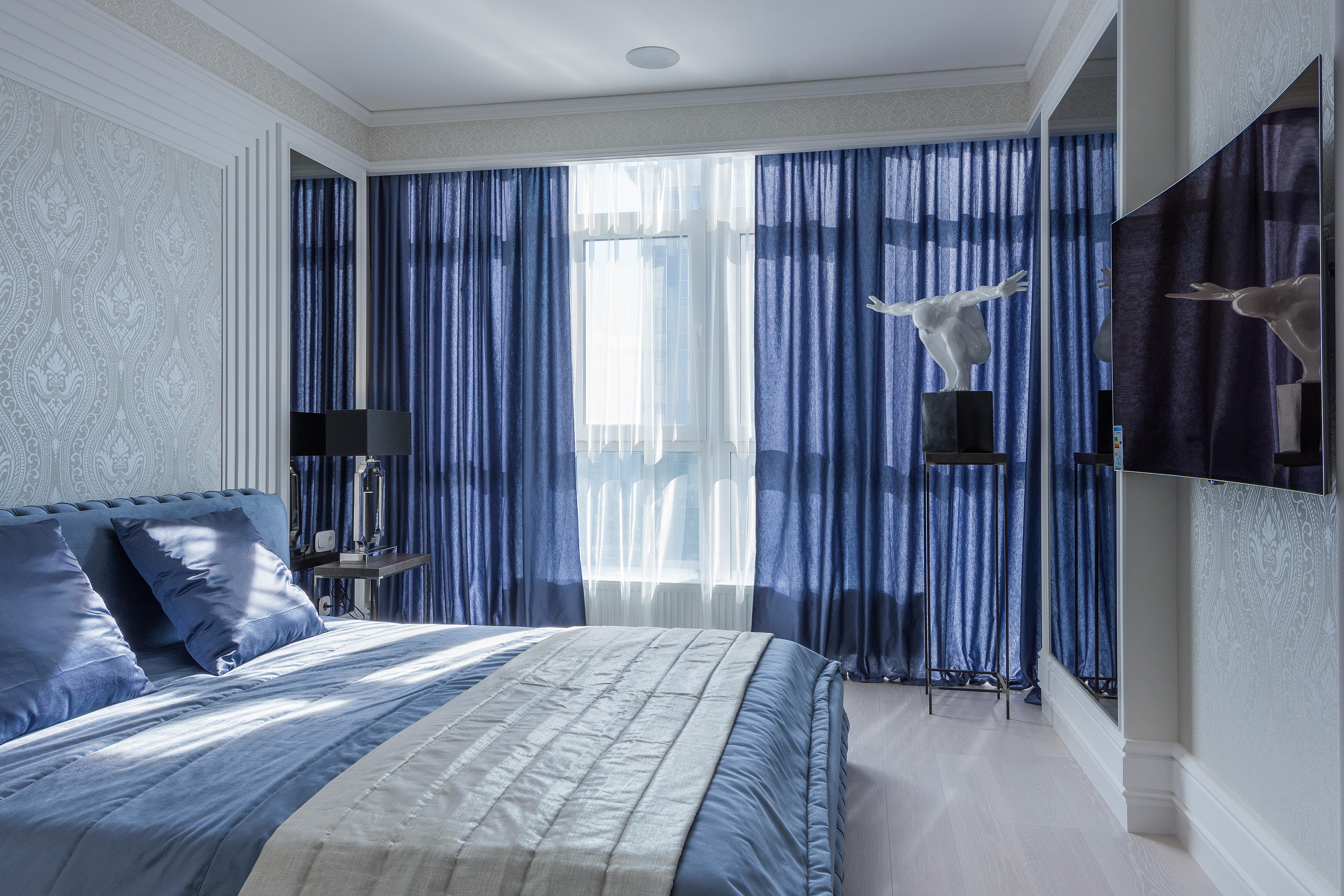Bedroom with pearl wallpaper and blue curtains.