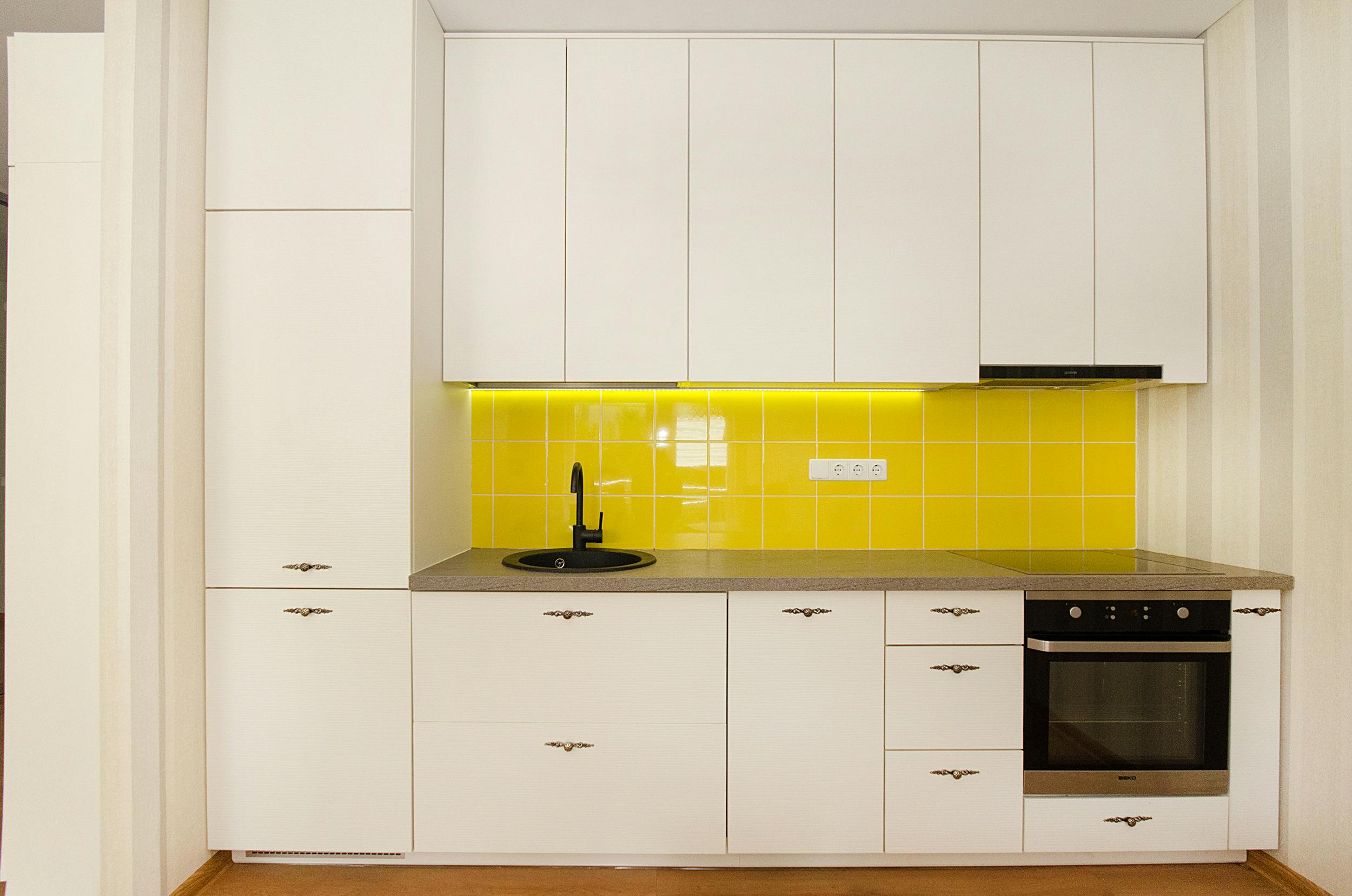 Cream kitchen with yellow backsplash in a modern design.