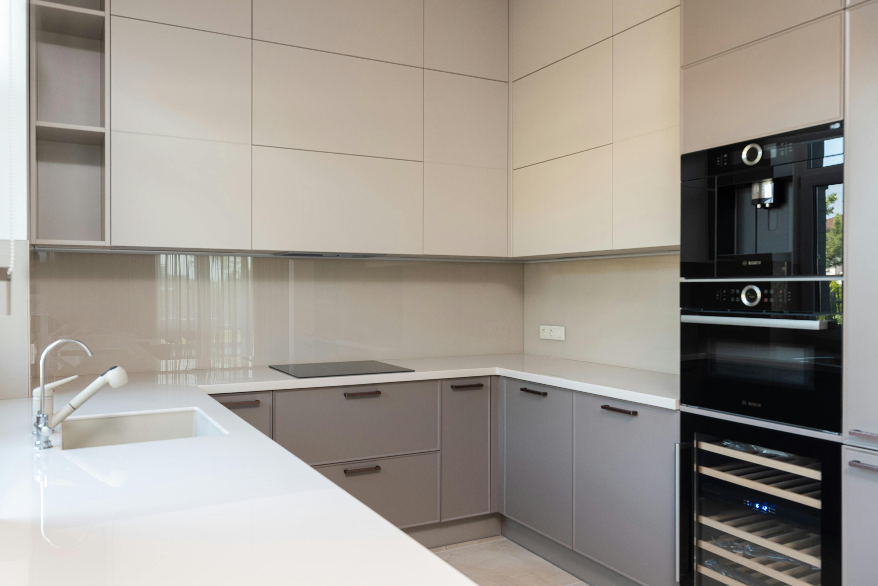 Kitchen with cream cabinets and a white countertop, featuring an oven and sink.