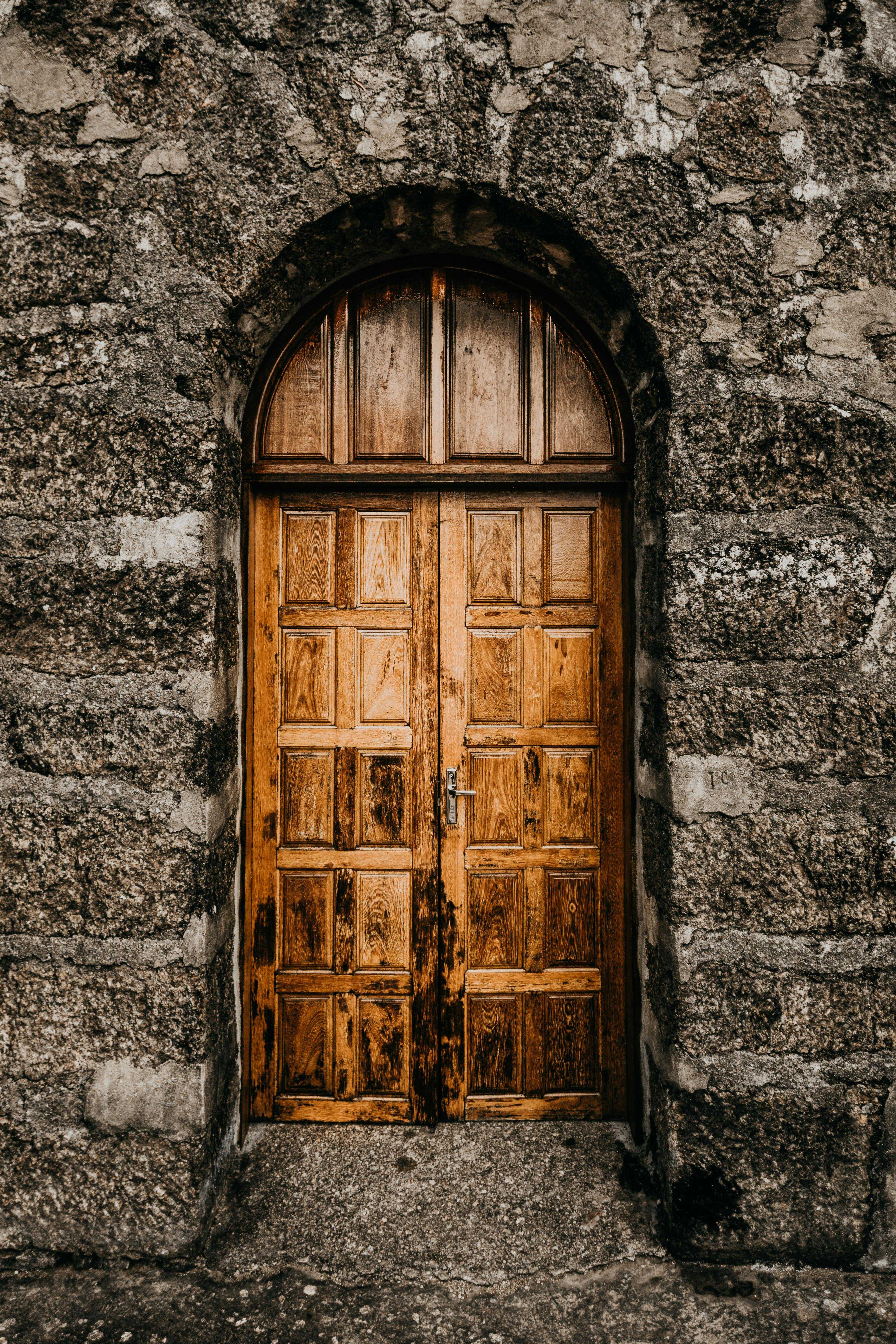 A brown wooden door set within a stone wall exterior, reflecting medieval architectural style with sturdy, rustic materials.