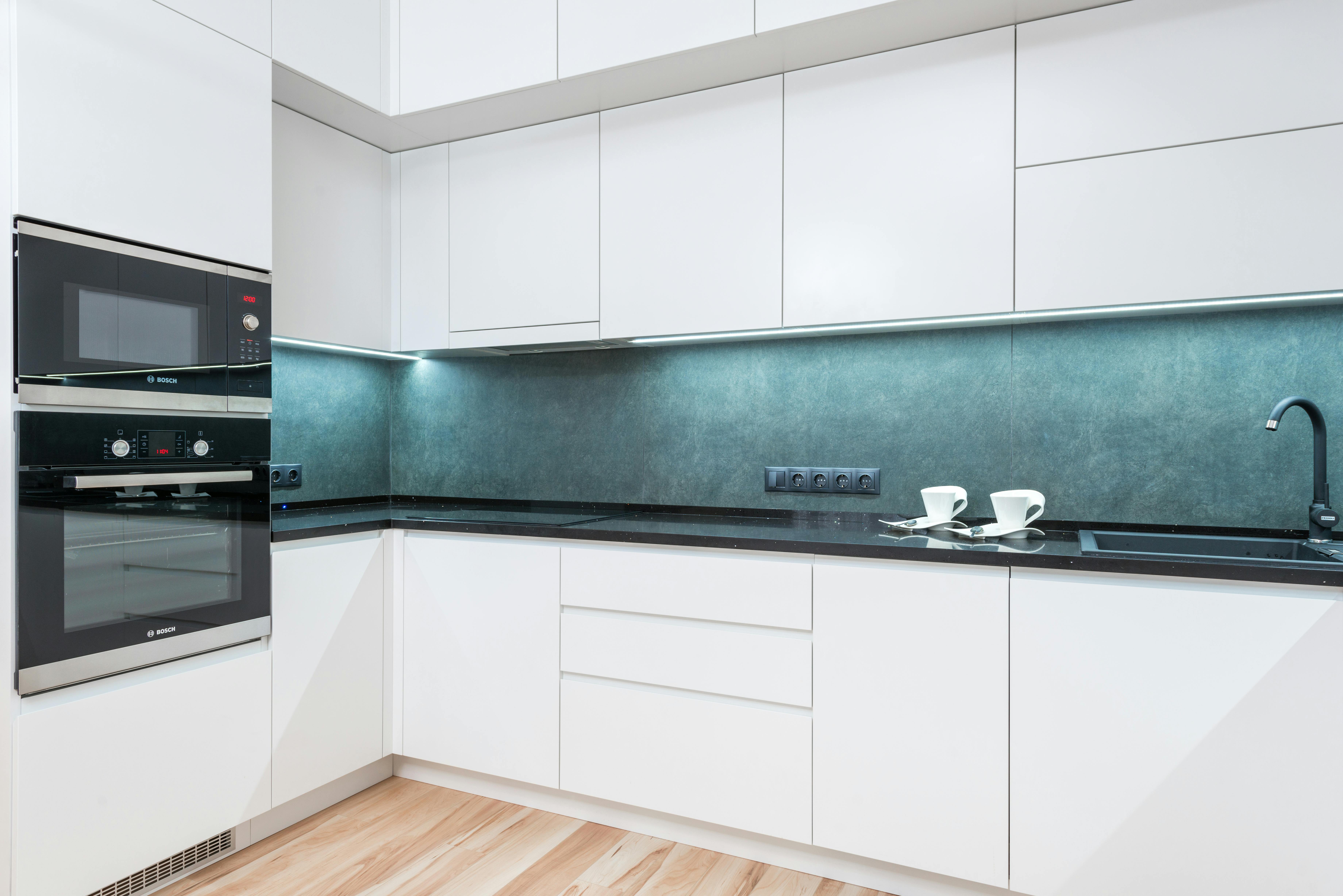 Minimalist kitchen with a blue backsplash, walls painted in Benjamin Moore White Dove, complementing wood tones.