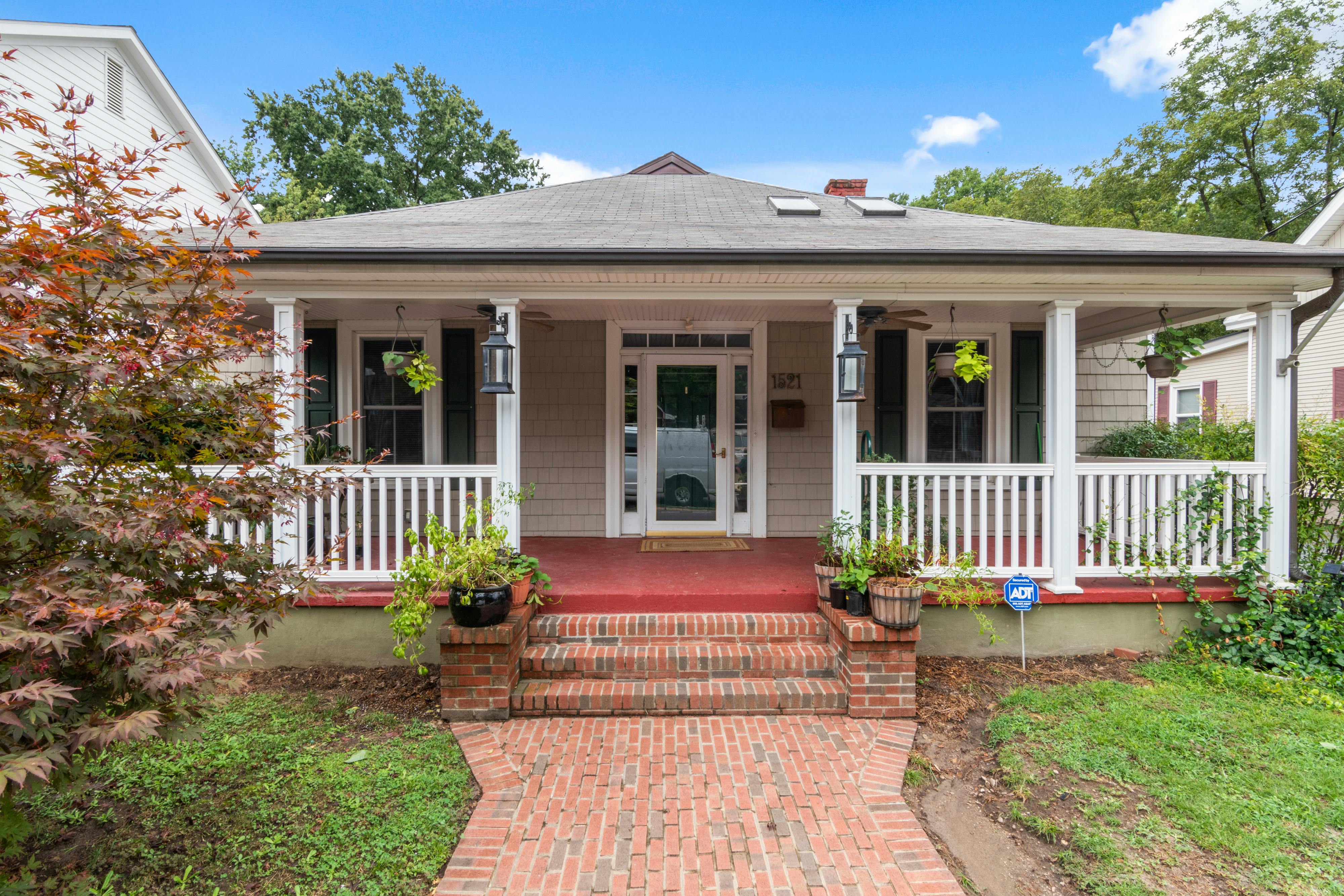 Stone walkway leading to a bungalow house with a covered front porch and landscaped garden.