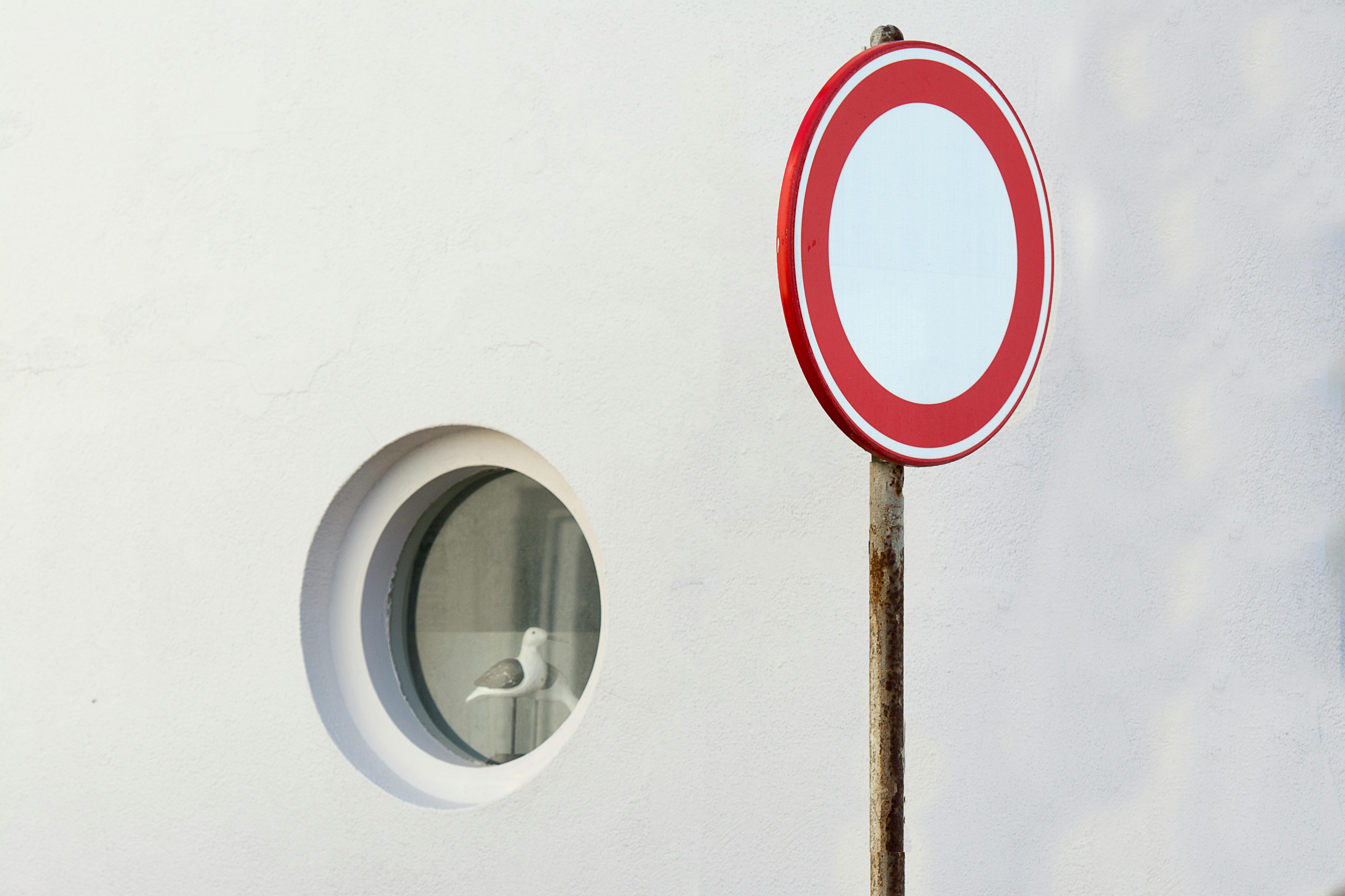Warning sign near a vessel window with circular shapes conveying fluidity and calm.