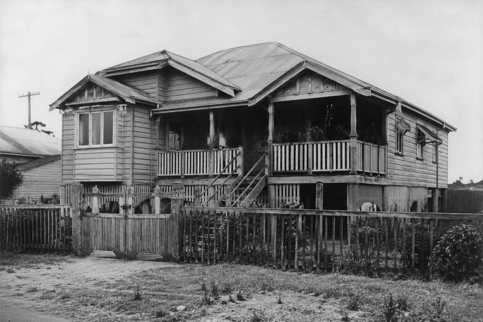 Restored Queenslander house with gabled roof, and front fence