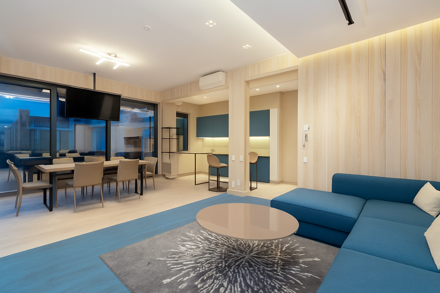Modern living and dining space with ocean blue sofa and blue kitchen cabinets paired with white surfaces.