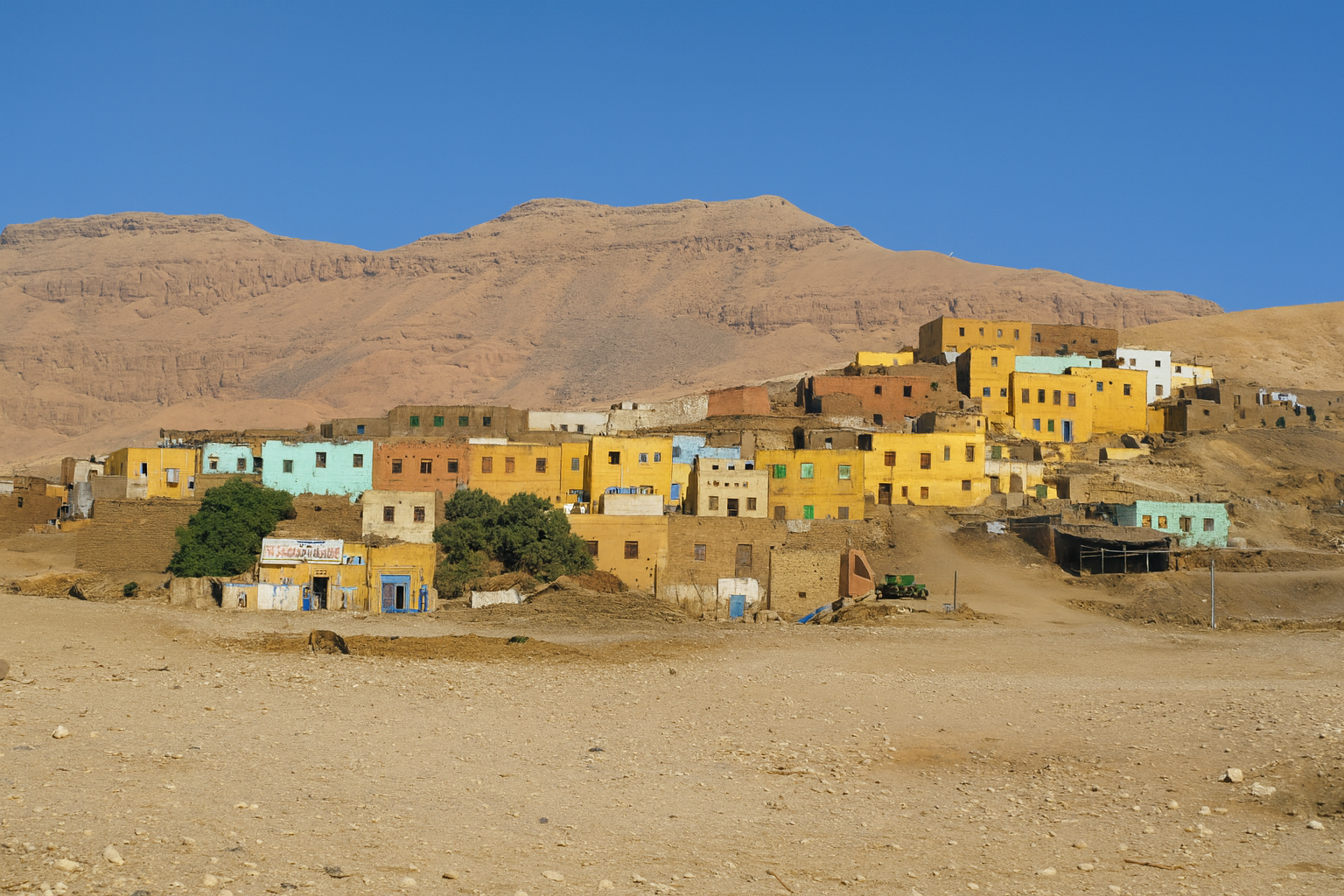 Scenic view of a hillside Gurna village in Luxor, Egypt, featuring vibrant clay houses clustered at the mountain base.