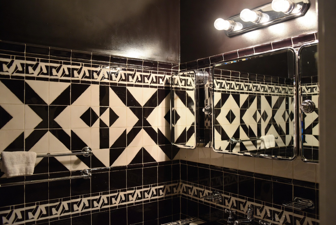 Bathroom with clawfoot tub, black-and-white floor tile, black border wall tile, and chrome fittings.