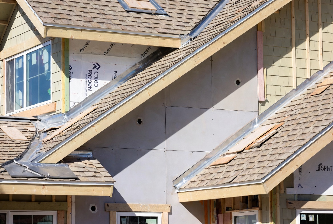 House exterior under construction showing wall cladding and roofing materials.