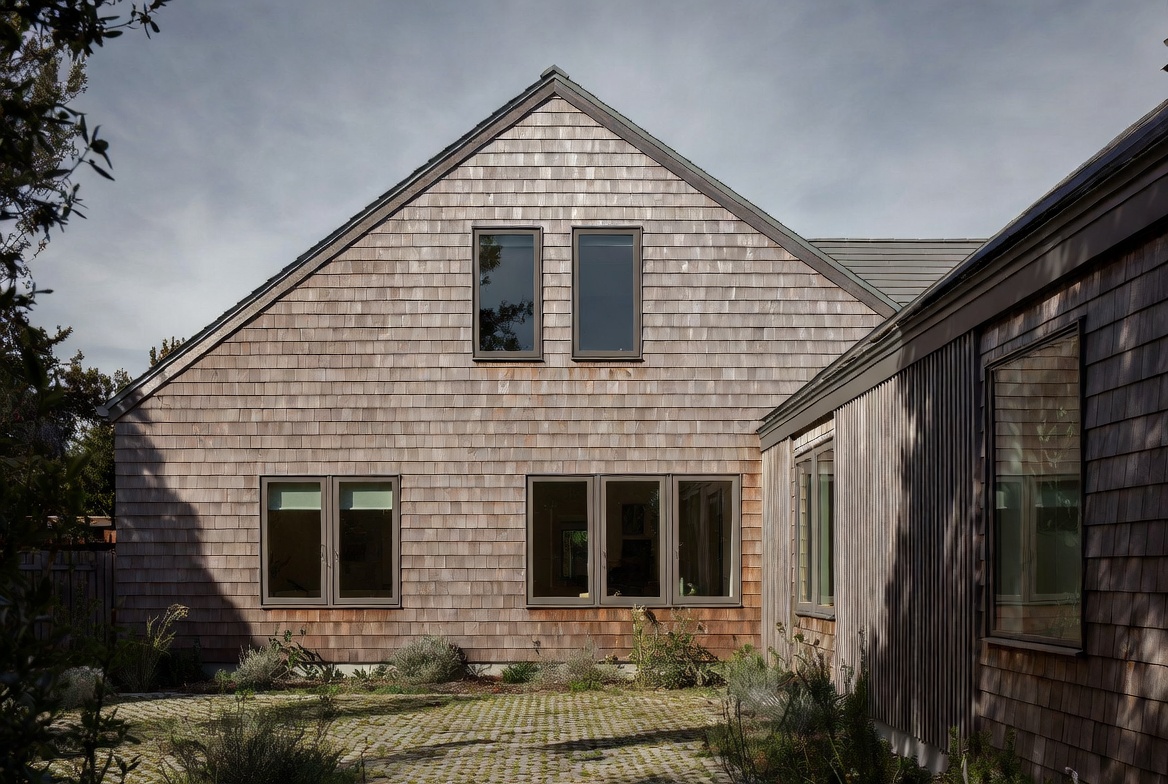 Finished house exterior with durable wood cladding, upgraded windows, and low-impact landscape surfaces.
