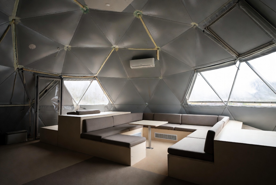 Compact geodesic dome interior with built-in seating, windows, and mini-split HVAC.