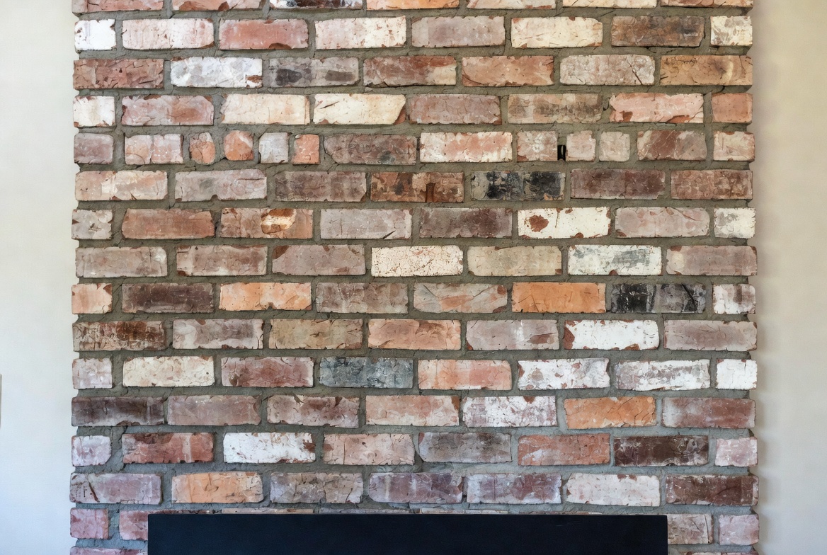 Reclaimed thin brick fireplace wall in a modest lived-in home interior.