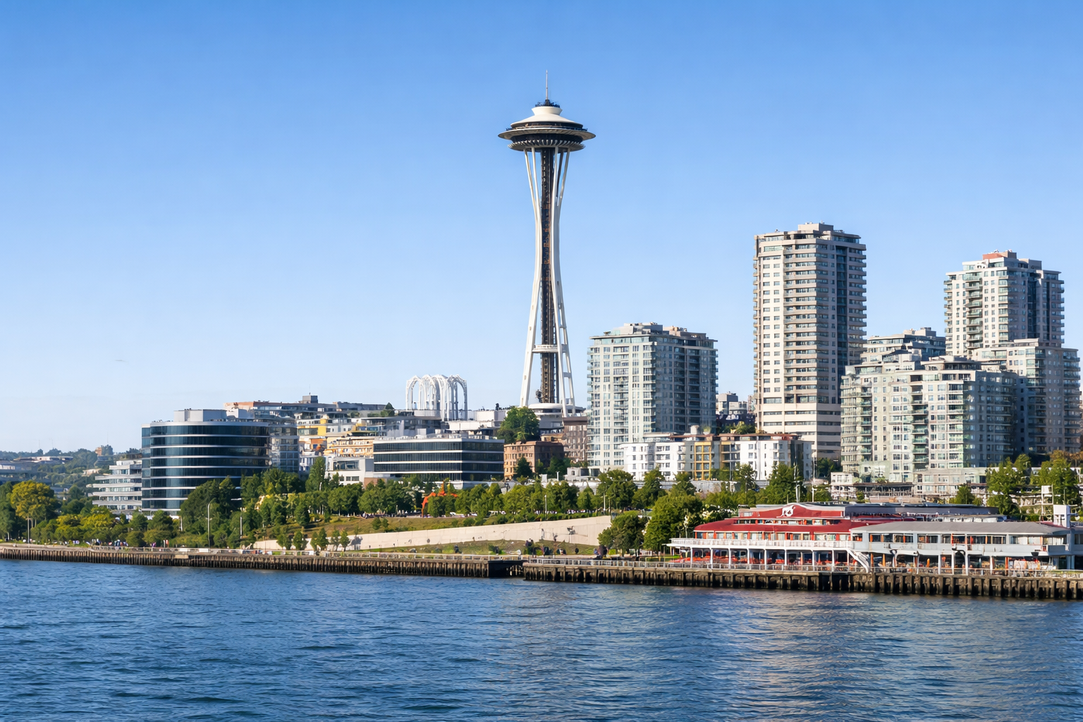 Seattle skyline with Space Needle under clear blue sky, waterfront view.