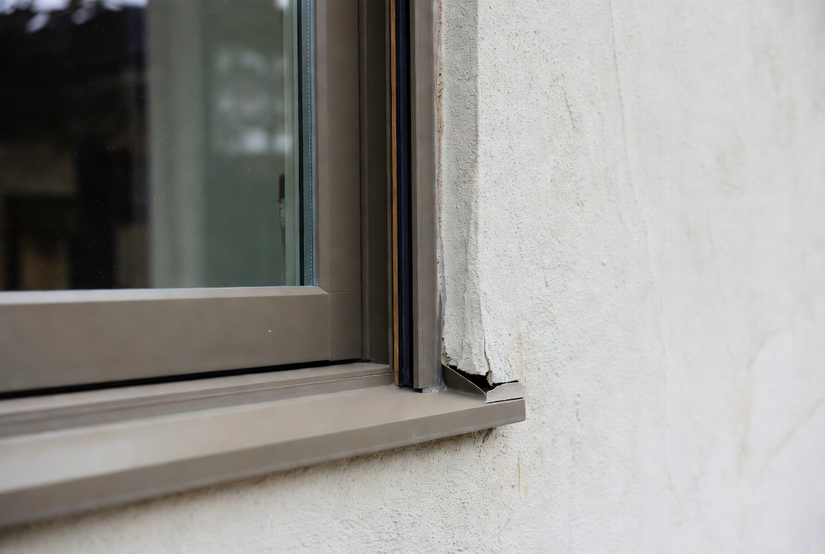 Close-up of a replacement window with flashing and trim integration at a renovated wall.