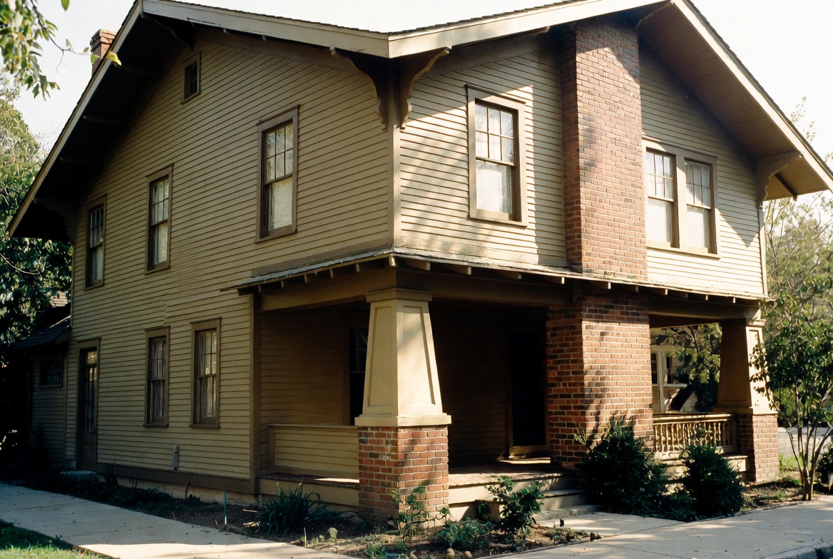 Authentic 1910s American house with broad porch, brick piers, deep eaves, and brick chimney.