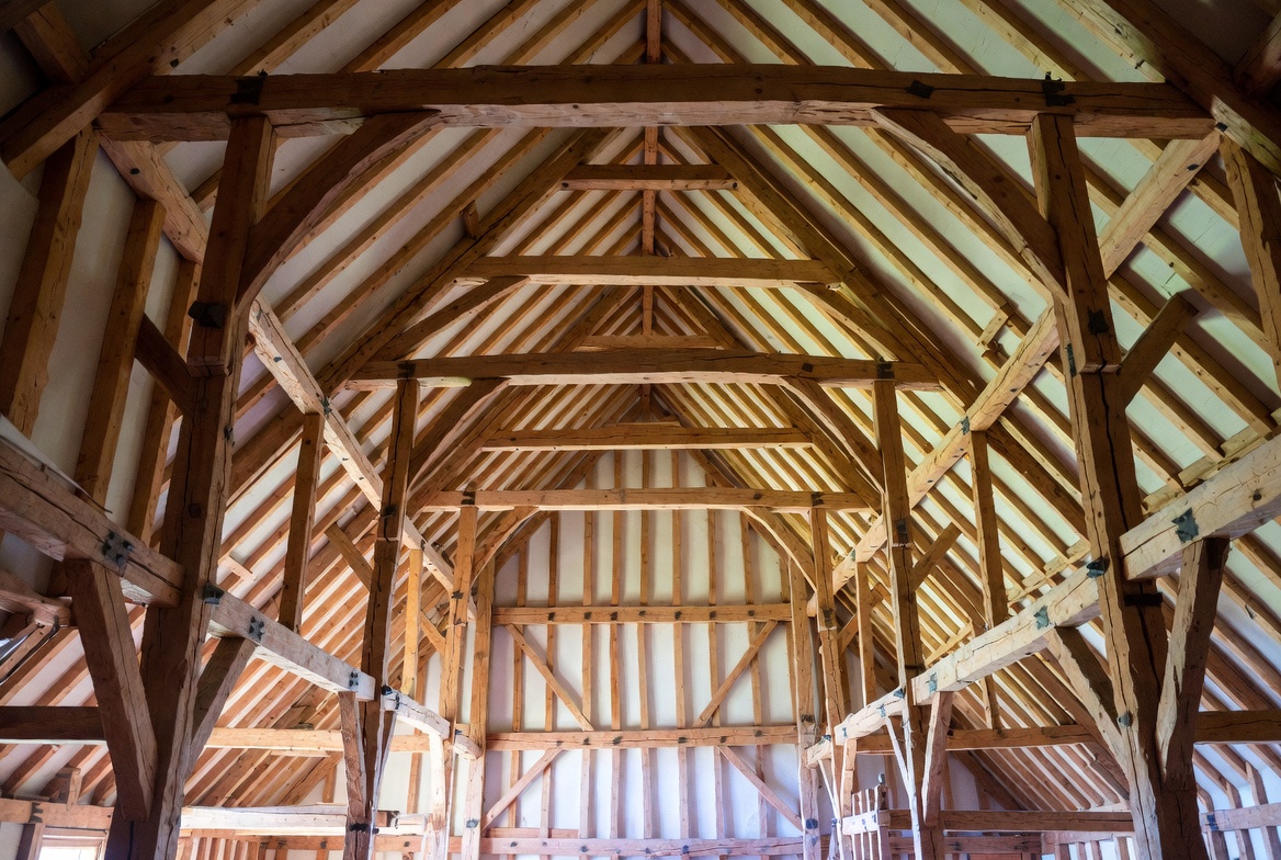 Timber hammer beam roof frame with open span and exposed rafters inside a large hall.