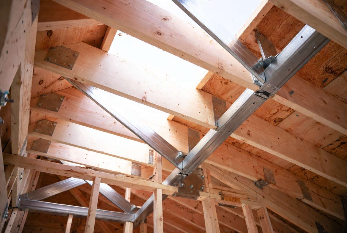 Metal roof brace connection fastened to rafters and framing members inside an attic roof.