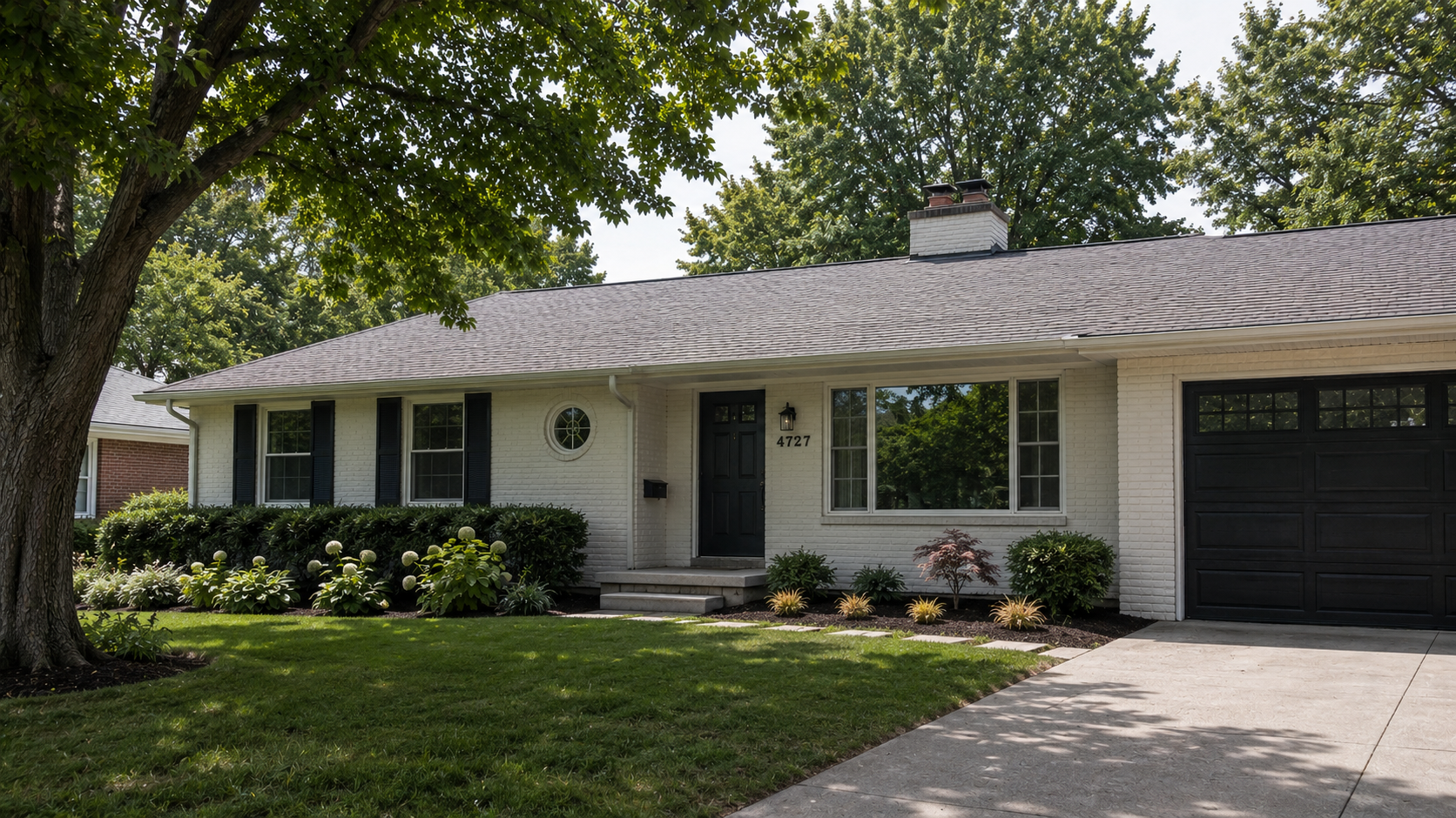 Updated ranch house exterior with white brick, black shutters, a dark garage door, low roofline, and restrained front landscaping.
