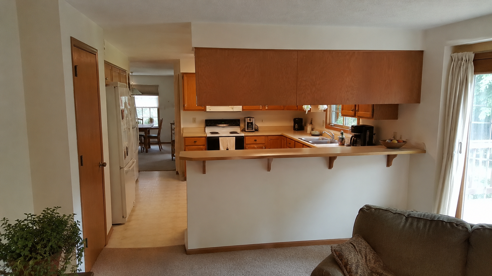 1990s kitchen with oak cabinets and a partial wall blocking the family-room connection.