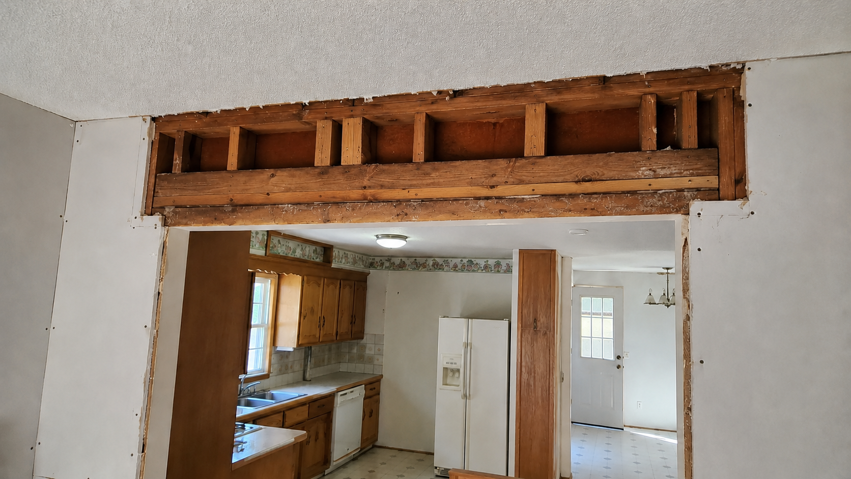 Opened wall above a ranch kitchen doorway showing exposed framing and drywall cuts.