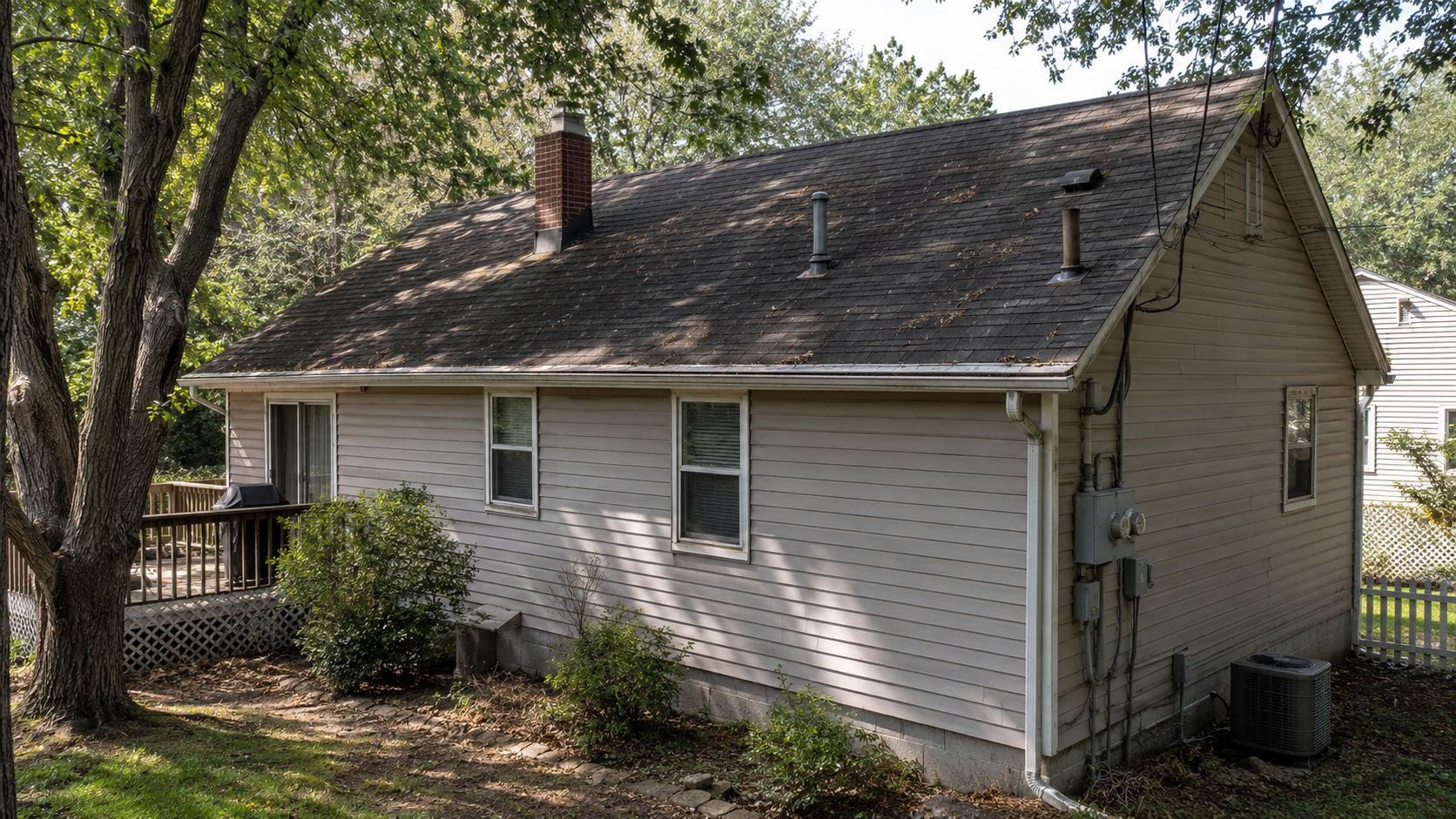 Older house roof with tree shade, vents, chimney, utility meter, and site conditions that complicate solar panel installation.