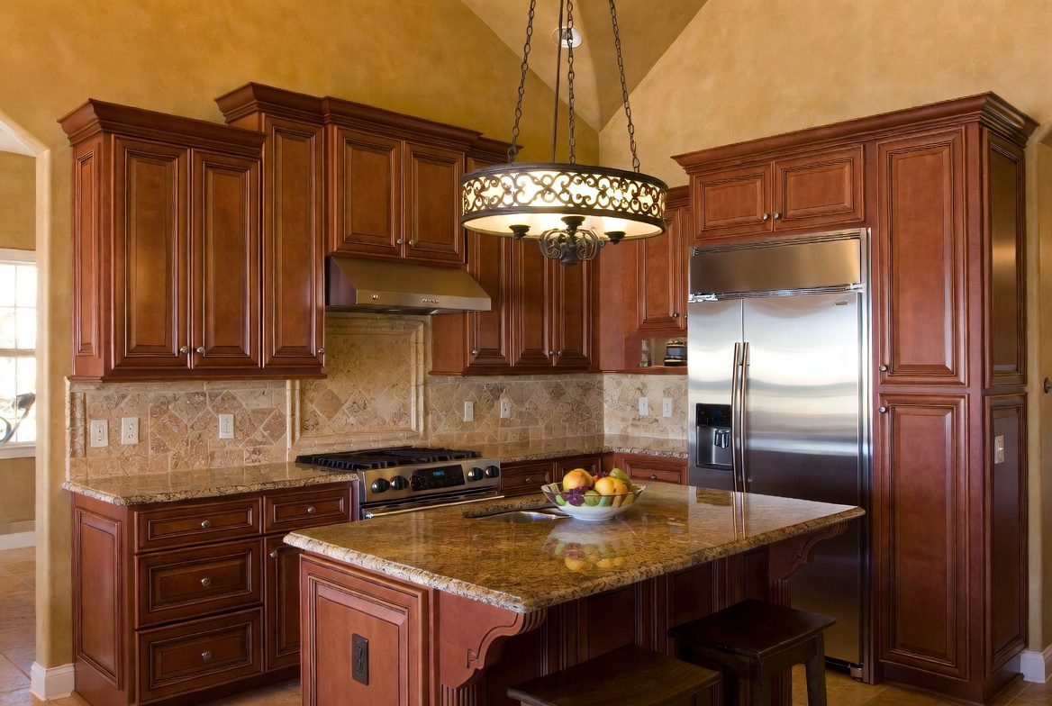 2000s Tuscan kitchen with cherry cabinets, granite island, travertine backsplash, and ornate lighting.