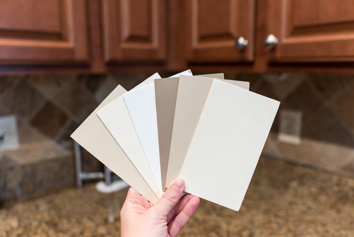 Paint samples tested against 2000s Tuscan kitchen granite, cherry cabinets, and stone backsplash.