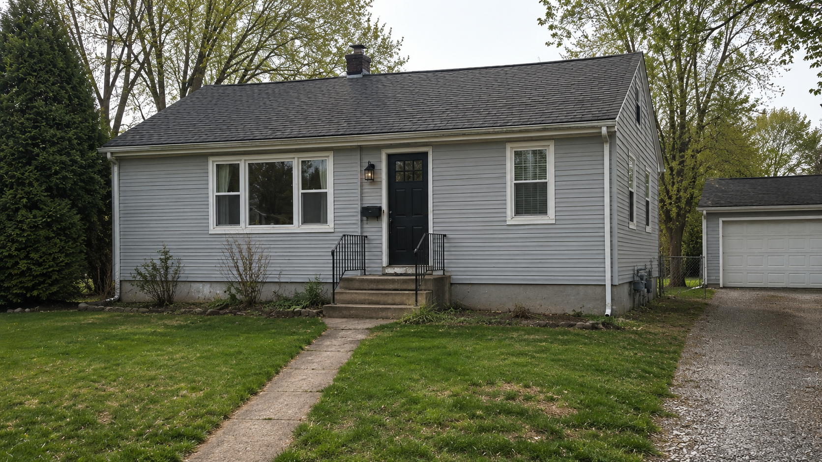 Plain 1950s bungalow exterior before porch renovation with small concrete stoop and weak curb appeal.
