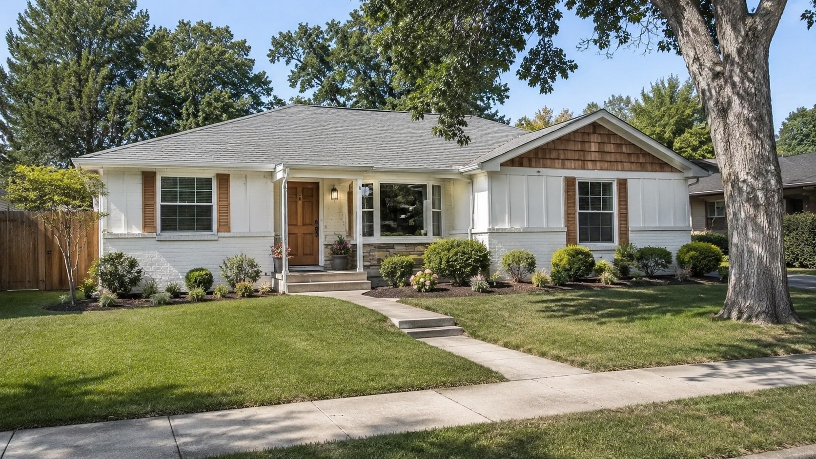 Updated 1980s ranch exterior with light siding, wood front door, simple landscaping, and low roofline.