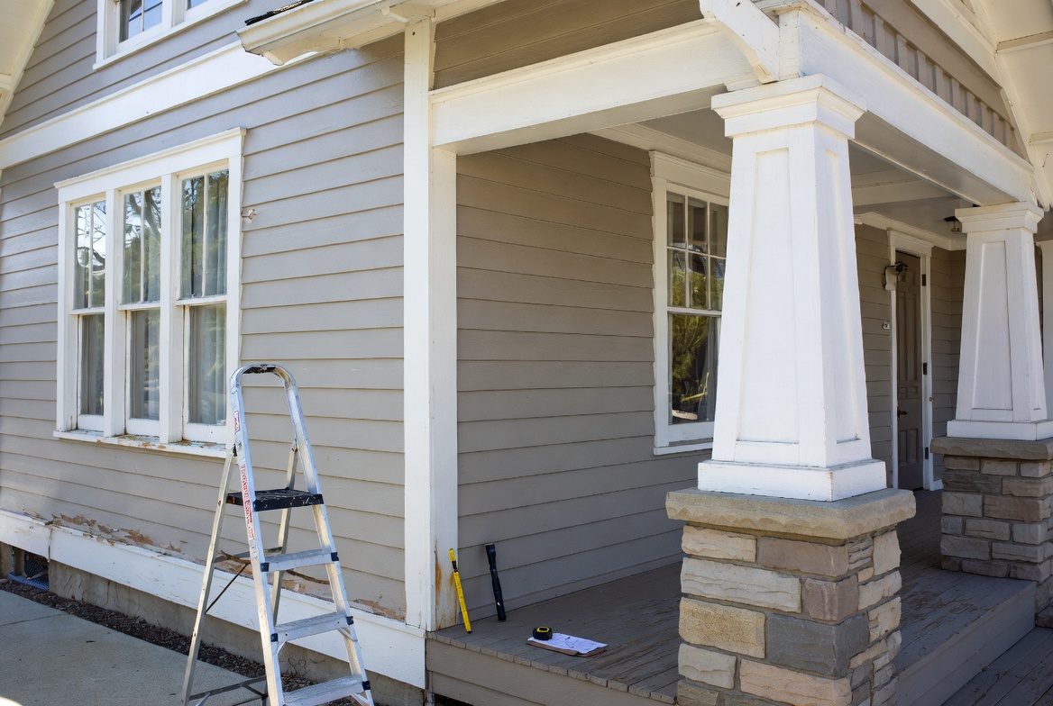 Craftsman exterior inspection showing siding, window trim, porch columns, and repair tools.