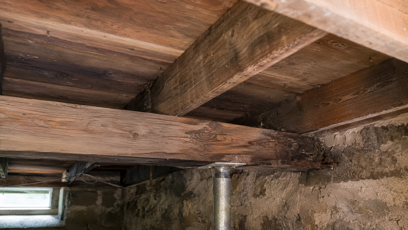 Moisture-damaged floor framing at an old basement foundation wall.