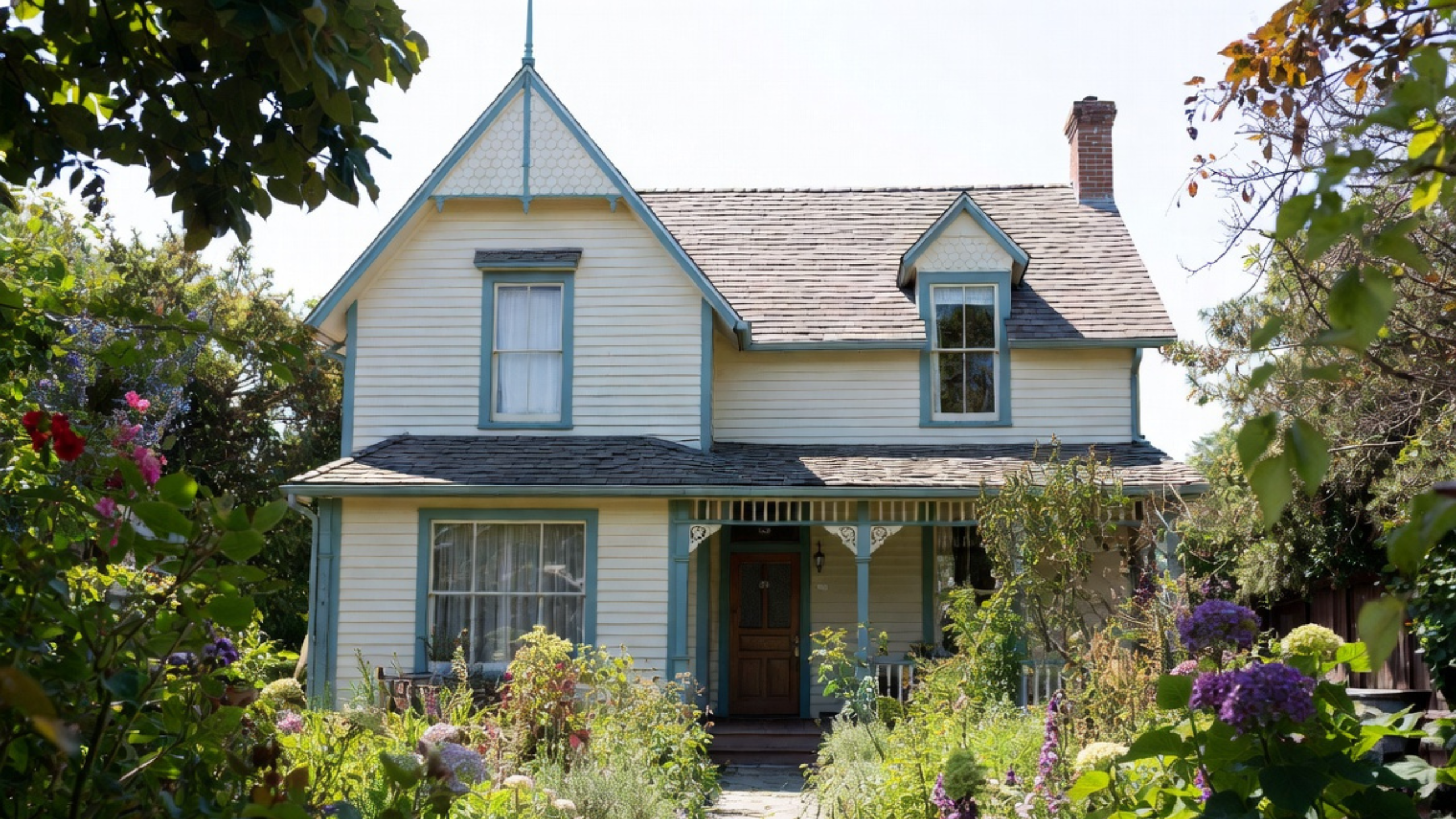 Late Victorian wood-frame house with a steep front gable, decorative trim, covered porch, and an established cottage garden.