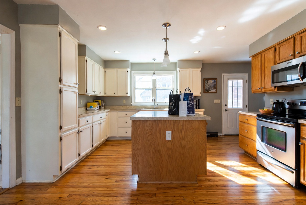 Partially updated kitchen with white painted cabinets, remaining oak cabinets, and a small island.