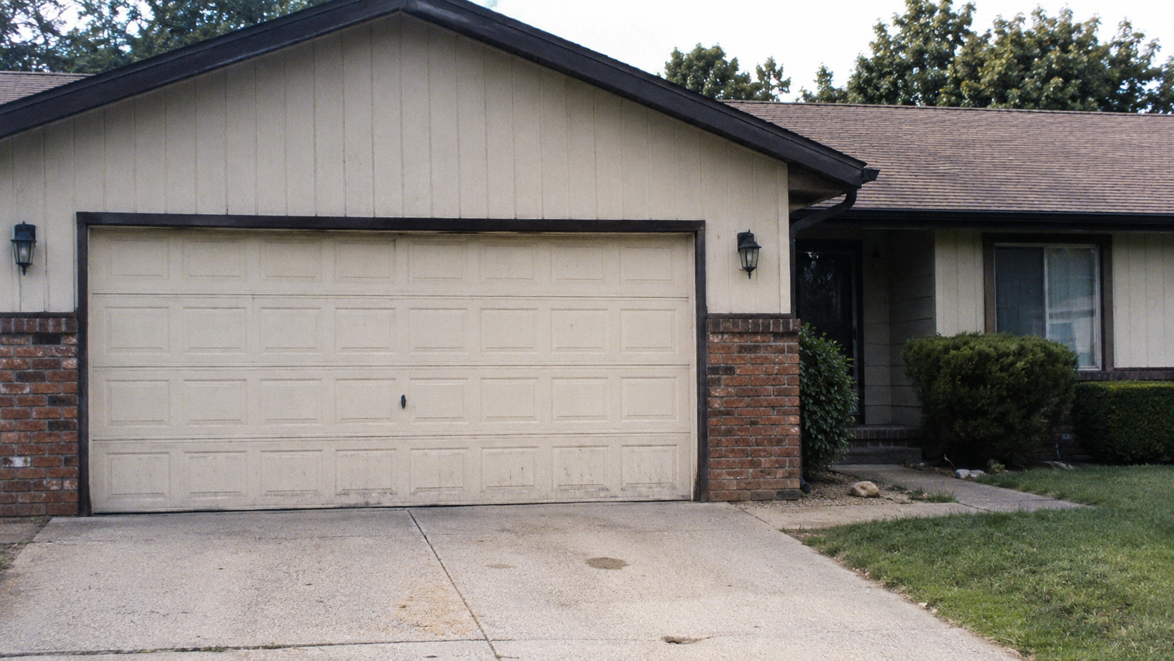 1980s ranch front garage and recessed entry with dated exterior materials.