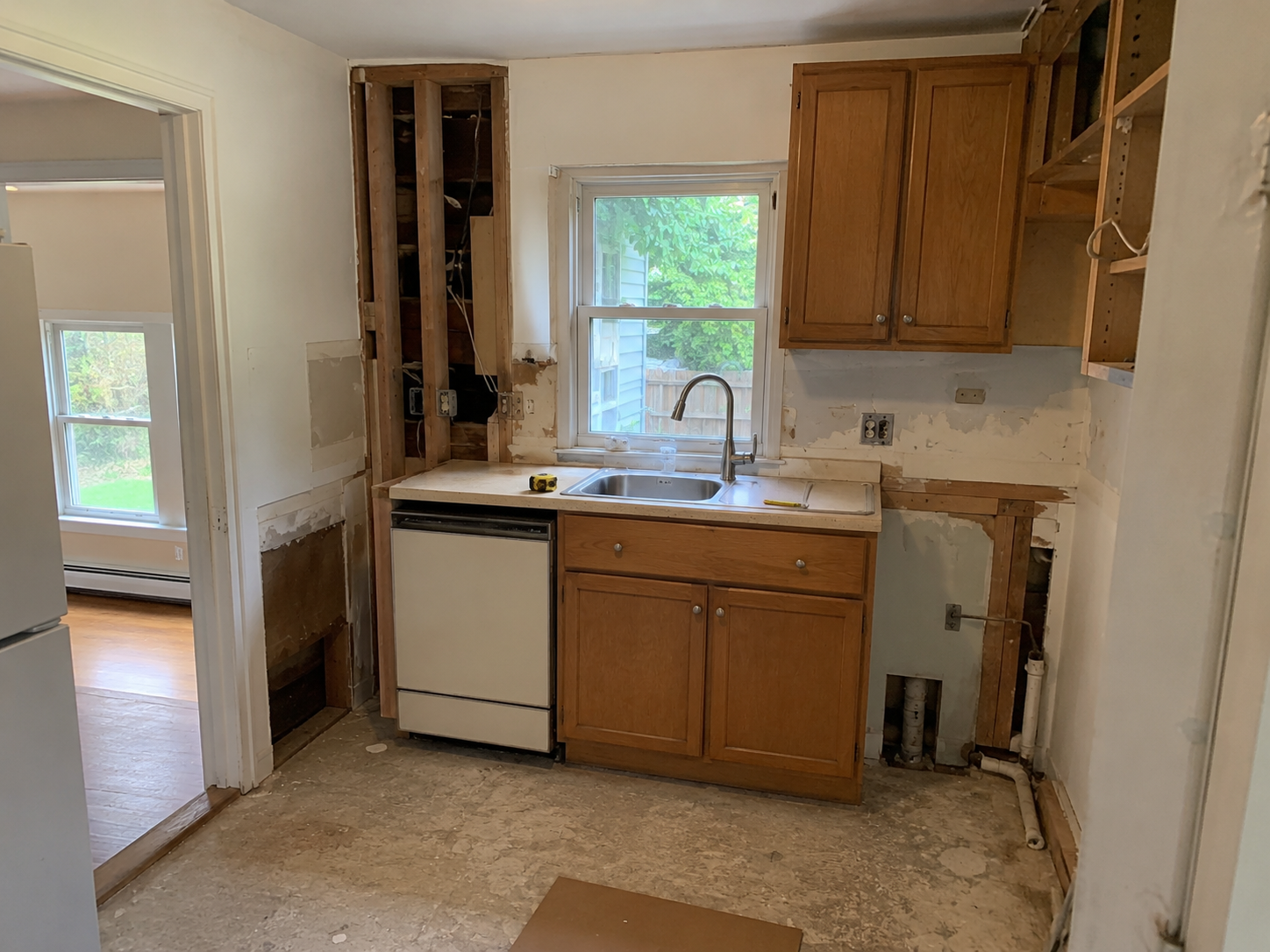 Small Cape kitchen during early demolition with cabinets partly removed and exposed wall areas.