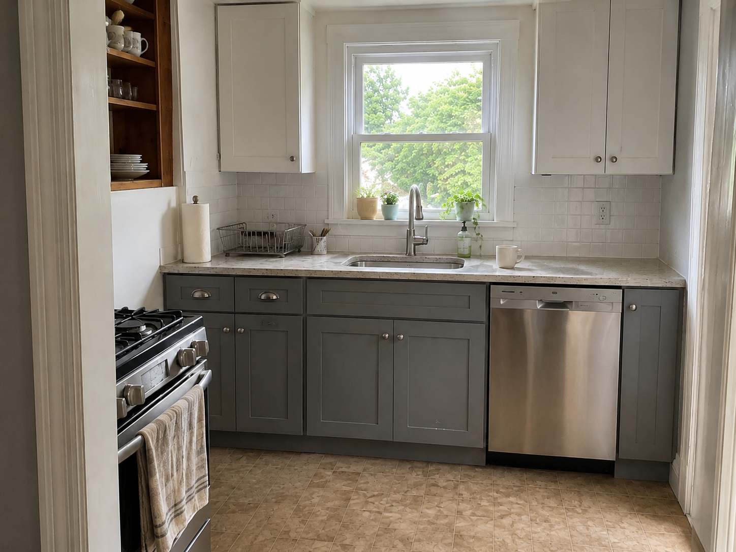 Small Cape kitchen remodel with gray cabinets, sink window, stove, dishwasher, and daylight.
