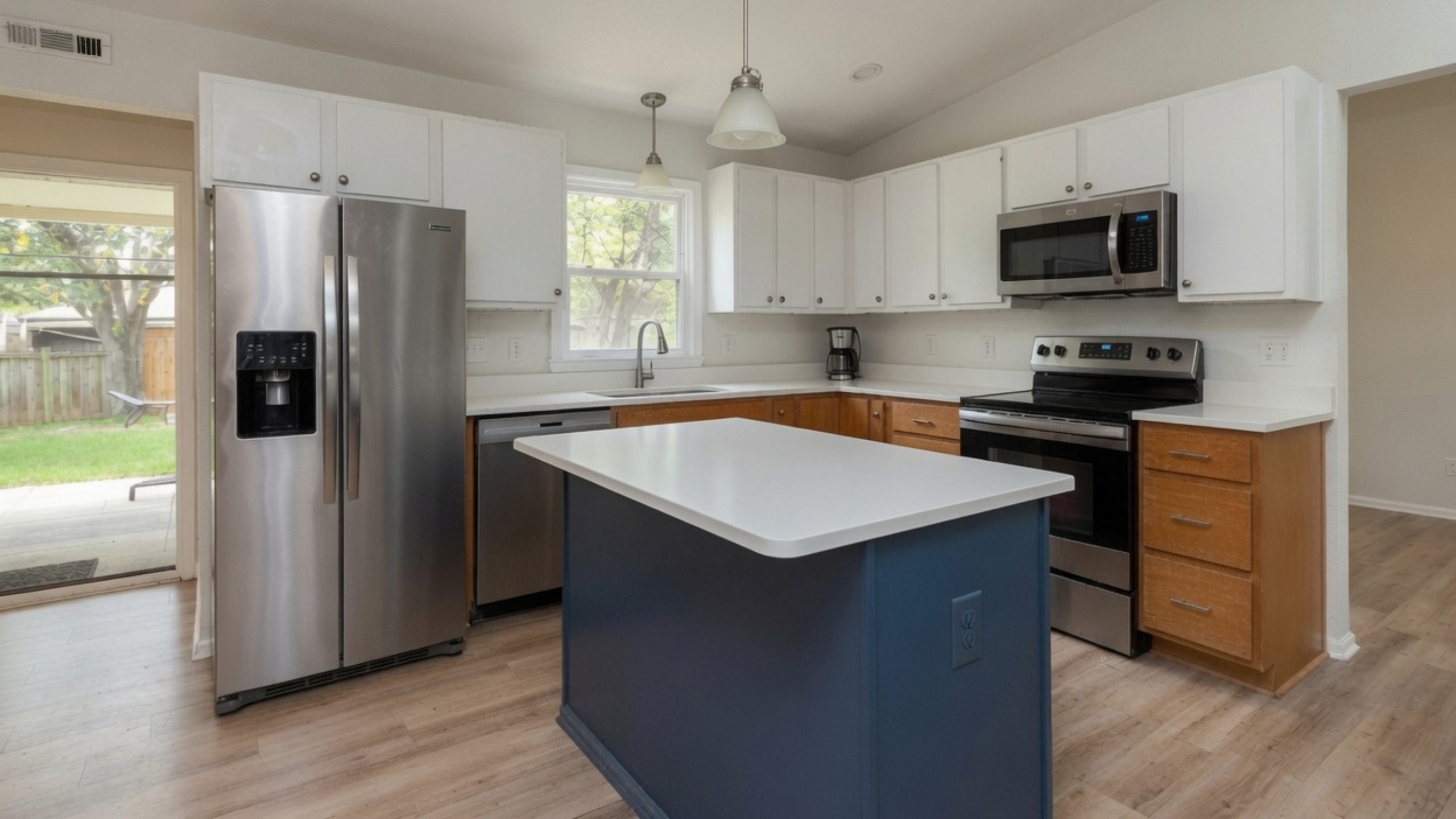 White upper cabinets, oak lower cabinets and a navy island in a compact remodeled kitchen.