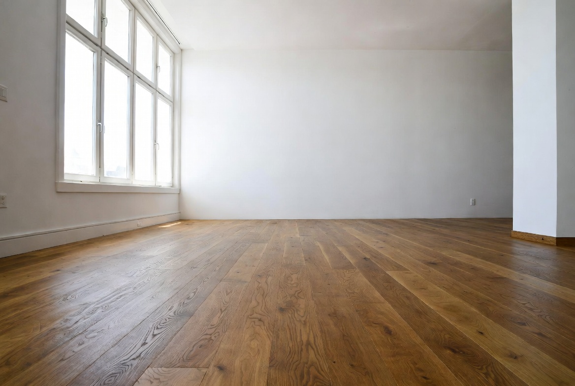 Wide-plank hardwood floor in a bright empty room.