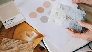 Architect holding a card over paper and a notebook, showcasing fundamental design elements.