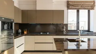 Modern kitchen with cream cabinets and black countertops, creating a classic contrast in design.