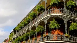 Colonial-style buildings in the French Quarter of New Orleans, featuring balconies and narrow streets.