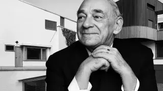 Portrait of Alvar Aalto with one of his architectural works behind him, reflecting his modernist approach that harmonizes design with the surrounding environment.