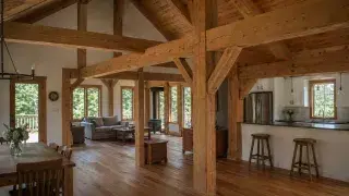 Post and beam home interior with exposed timber posts, beams, knee braces, and vaulted roof framing.